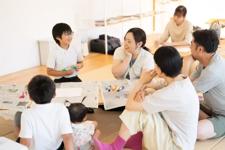 260611 oyakoyudo 16 w1440 床に敷いた新聞紙を囲み、講師と言葉を交わしながら考える親子