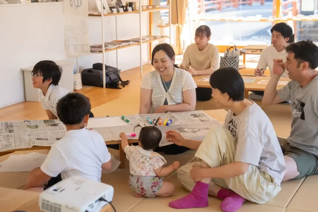 260611 oyakoyudo 33 w1440 新聞紙を広げた座卓を囲んで話し合う親子