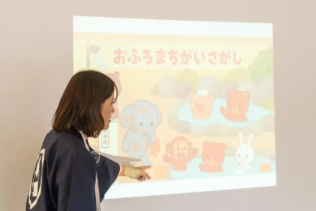 260611 oyakoyudo 36 w1440 6月の教室で、「おふろまちがいさがし」のスライドを指して説明する講師