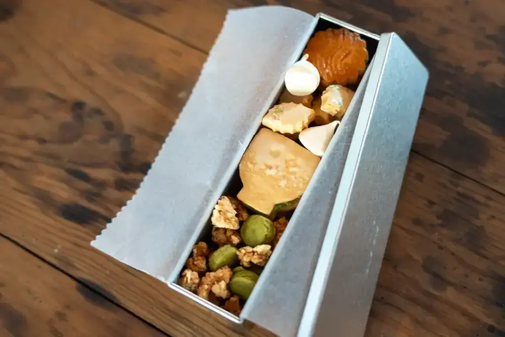 pc slide2 1024x683 1 木のテーブルに置かれた、焼き菓子が詰められた銀色の菓子缶