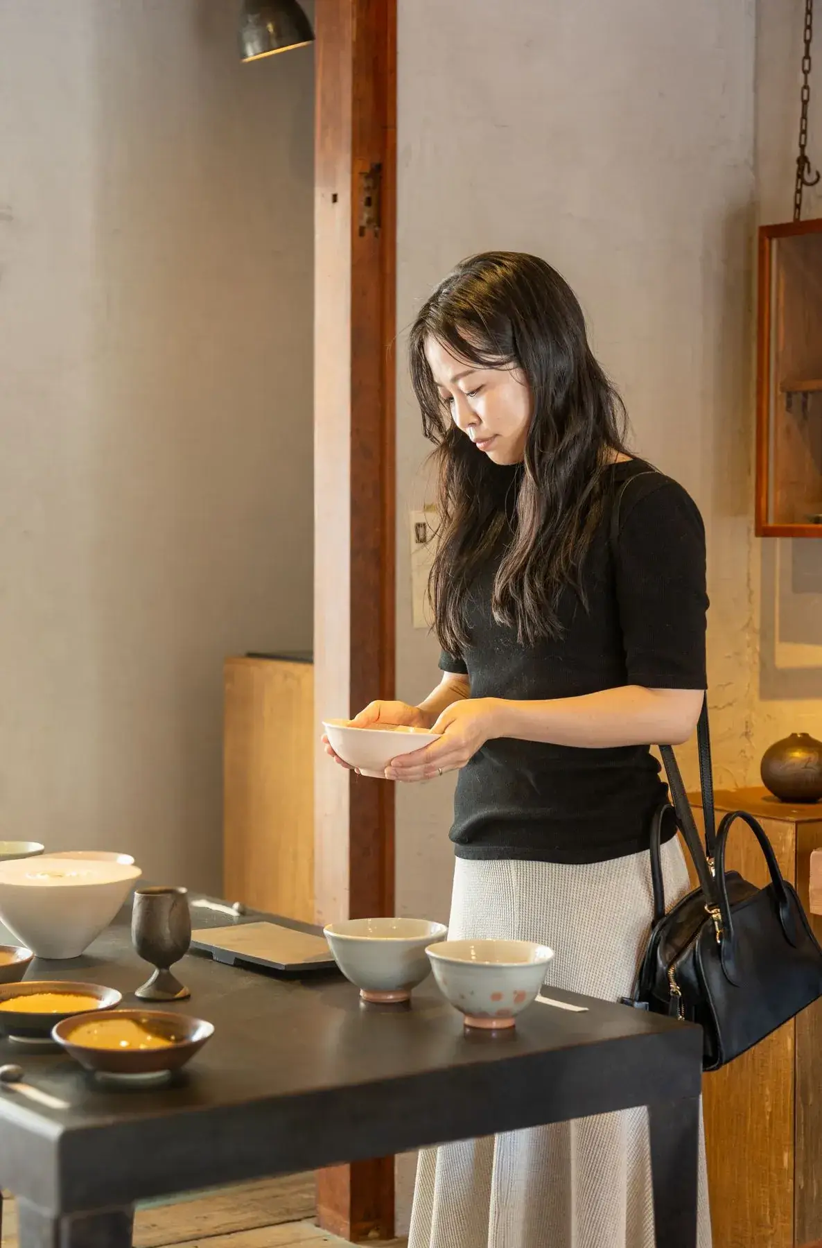 器の並ぶ店で、両手で持った器を眺める女性