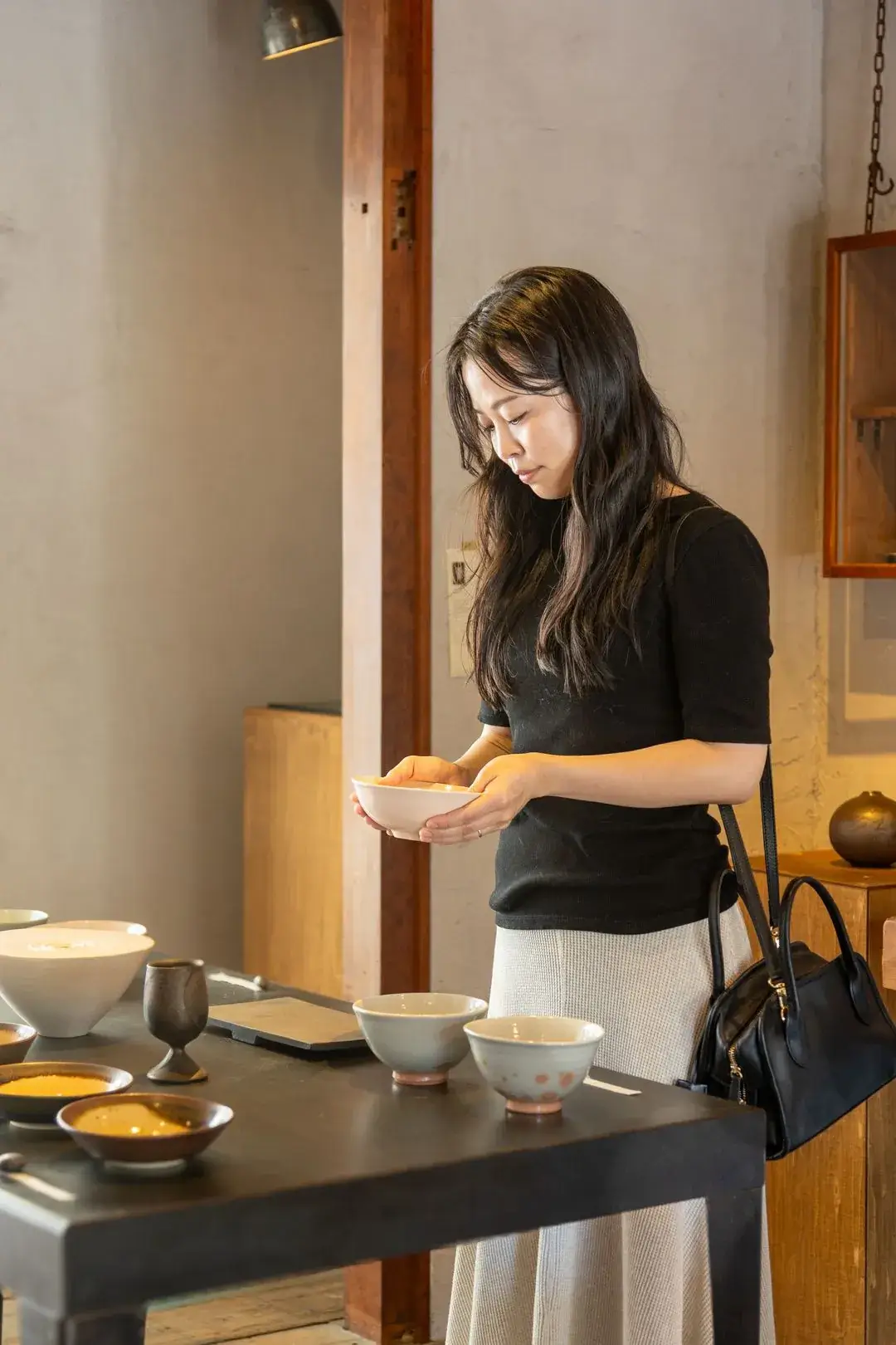 器の並ぶ店で、両手で持った器を眺める女性