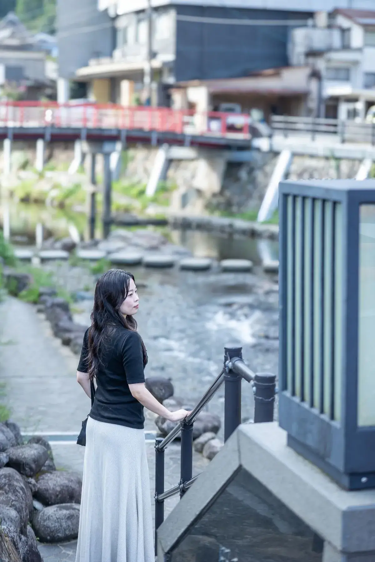 川沿いの手すりにもたれて川を眺める女性