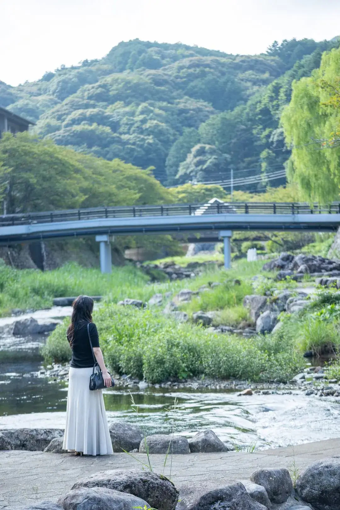 朝の音信川のほとりに立つ女性